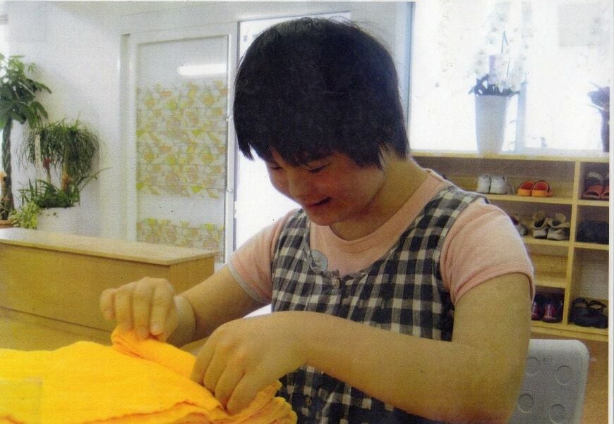 現在の梓さん。障害者就労支援施設でタオルたたみの仕事をしている（写真：是松いづみさん提供）