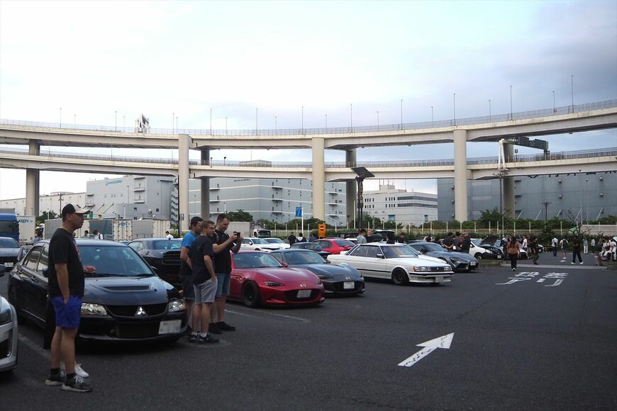 日本のスポーツカーや旧車にカメラを向ける外国人観光客（筆者撮影）