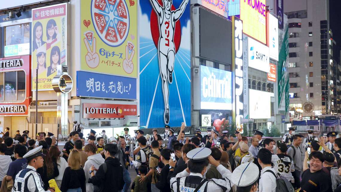 阪神が38年ぶりに日本シリーズを制し、戎橋で盛り上がるファンら(写真:時事)