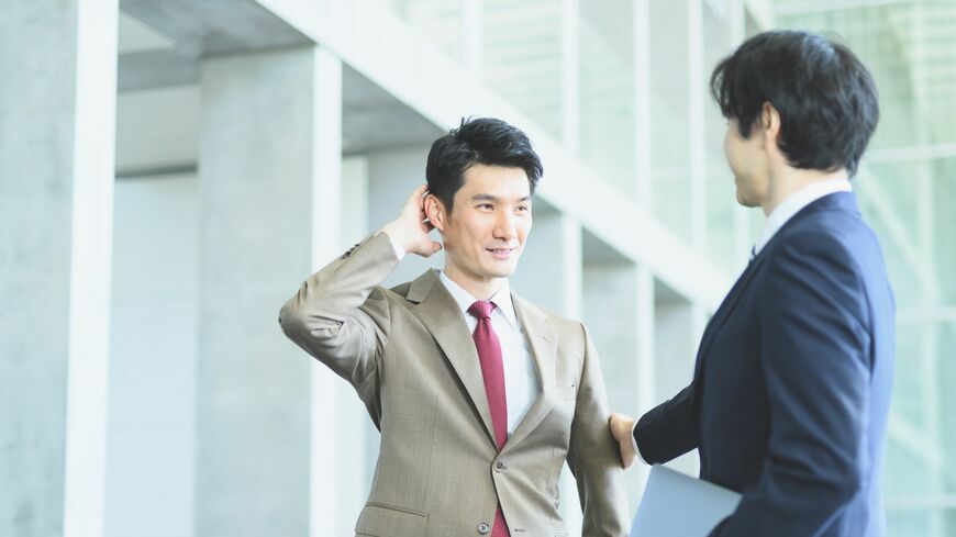 褒められて照れるスーツの男性