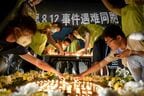 病院の前で犠牲者の冥福を祈る人々