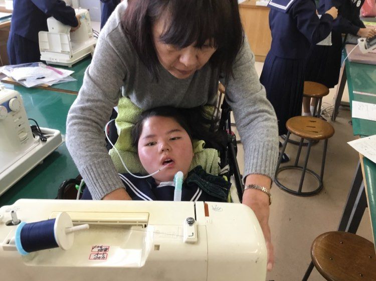 ミシン縫いを体験する京香さんと稲田前校長（写真：ご家族提供）