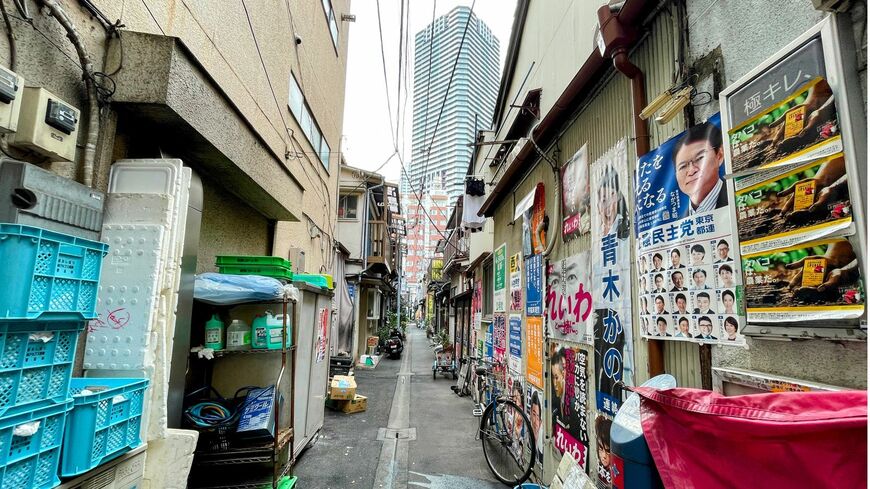 古い家屋の先に見える勝どきのタワマン（筆者撮影）