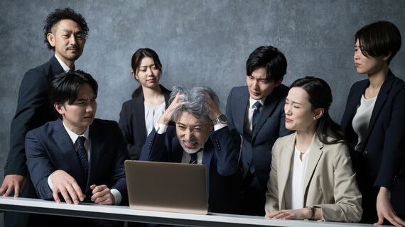 頭を抱える男性とビジネスチームのイメージ
