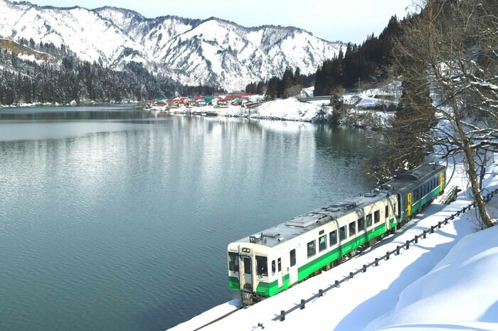 会津川口付近、雪景色の山並みと水鏡に映る集落