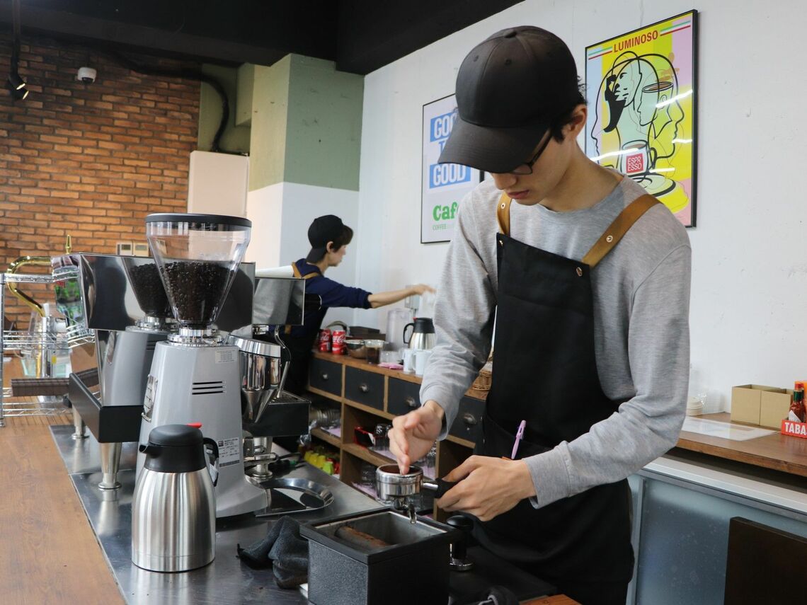 コーヒーを淹れる岩村さん（仮名）。笑顔で注文に応じていた（記者撮影）