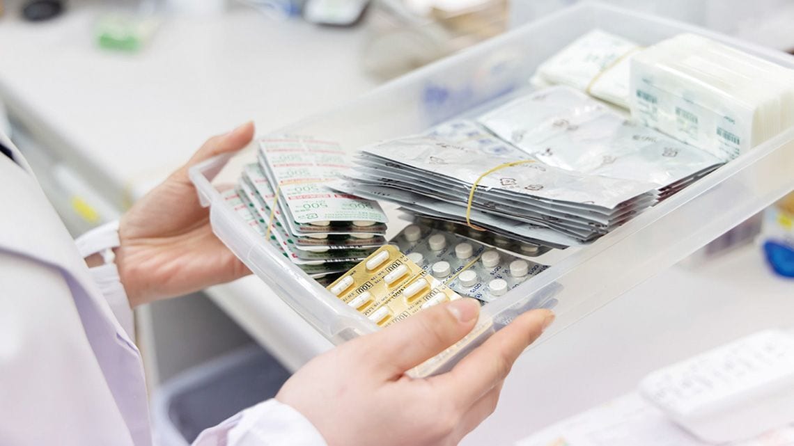 薬の入ったトレイを持つ薬剤師