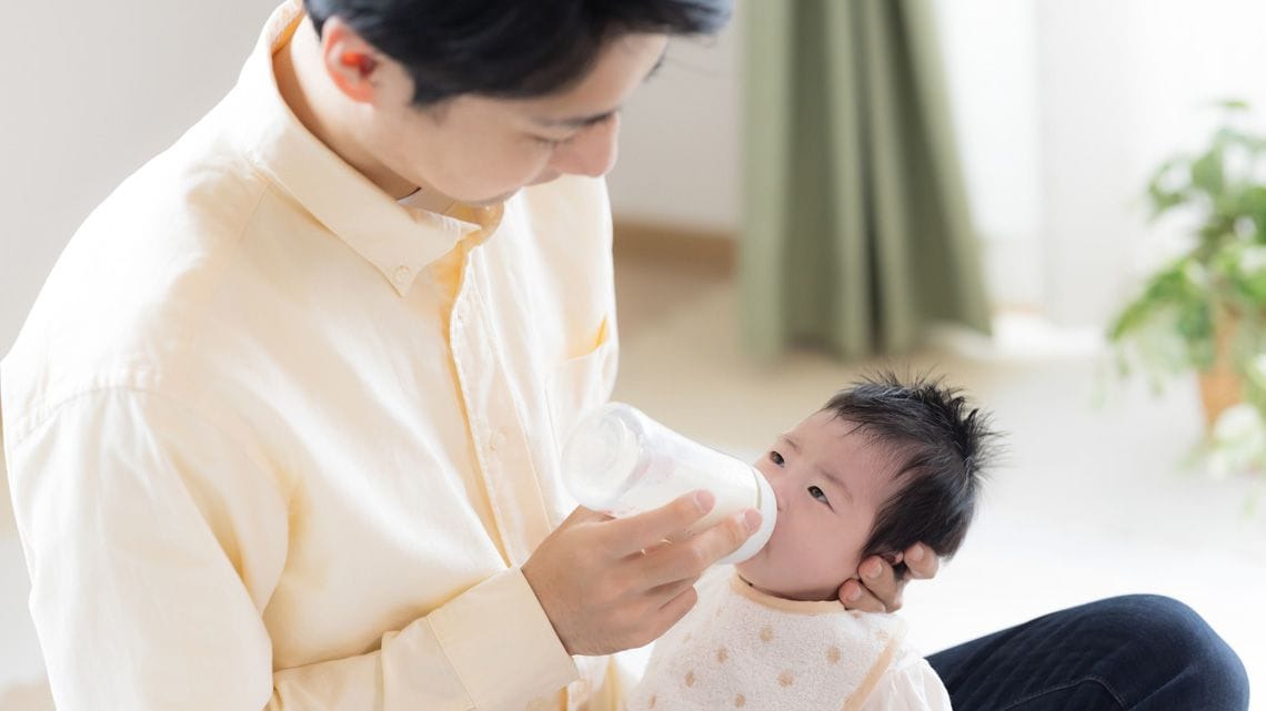 乳児にミルクを飲ませる父親