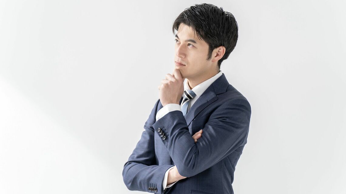 顎に手を当てて、考えるビジネスマン