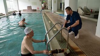 温泉プールで患者さんと話をする岡田医師
