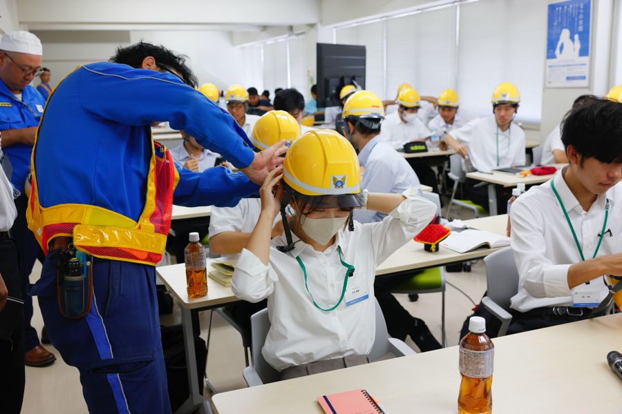 社員の手助けを受けつつ慣れないヘルメットを着けて、いざ現場へ（写真：村上悠太）