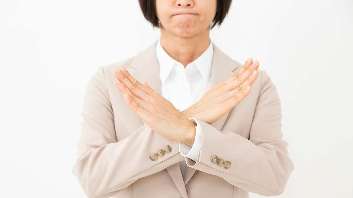 手でバツをつくる女性