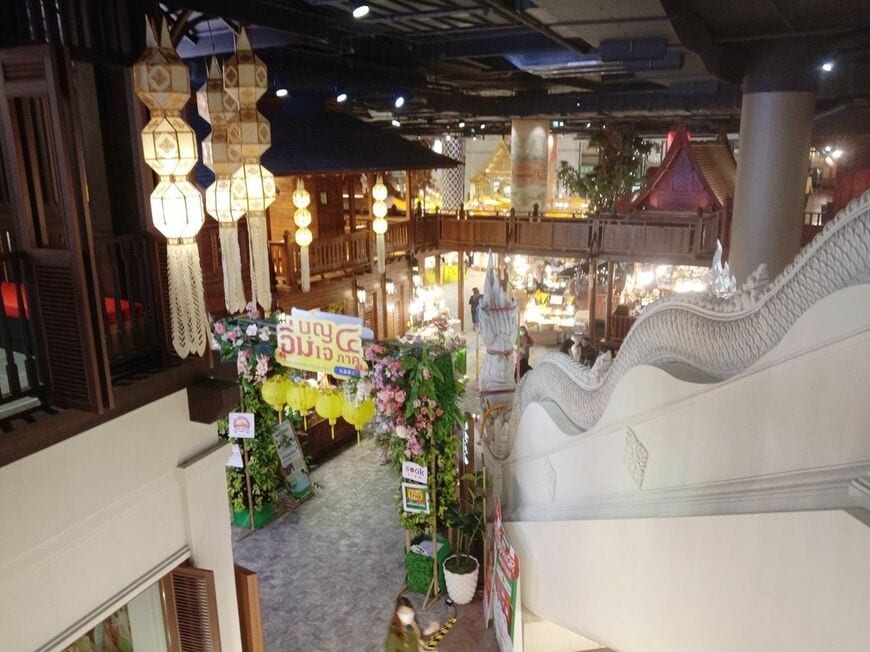 ショッピングモール「アイコンサイアム」の館内で、２階から見下ろした１階の昔のタイを模した町並み。右に映っている階段の手すりにはタイの蛇神ナーガをあしらってある。こちらは北部チェンマイ県のドイステープ寺院の階段を模した物（写真：筆者撮影）