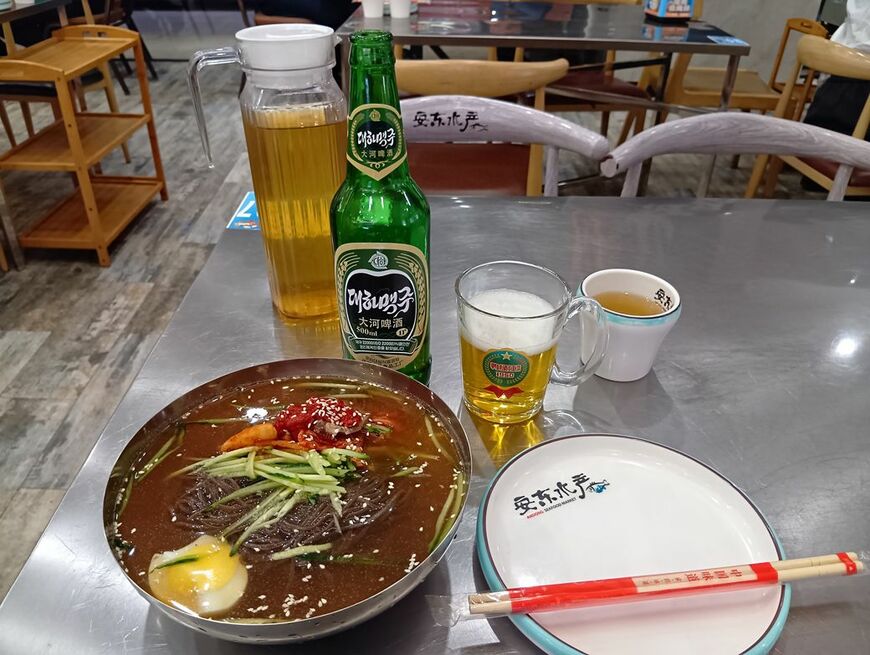 麺がモチモチの平壌冷麺。油っぽい料理に合いそうな「大同江ビール」と一緒に（写真：筆者撮影）