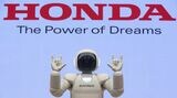 ホンダのロゴを背景にポーズをとるアシモ