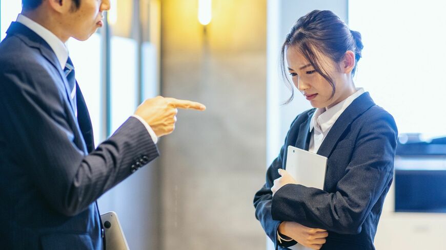 パワハラで若い女性の部下を叱るおじさん上司