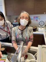 デイサービスで食器洗いの手伝いをする伊東さん（写真：「世田谷中町」提供）