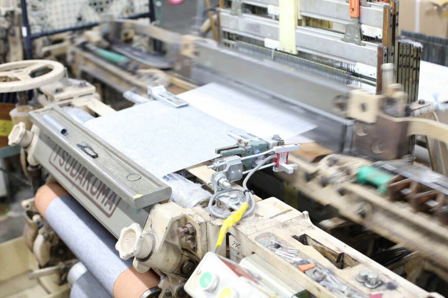 ガチャン、ガチャンと機を織る古い織機。以前は足踏み式だったが、現在はモーターを後付けして動かしている（写真：筆者撮影）