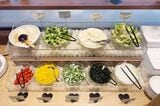 ジョナサンの朝食バイキングのサラダエリア。左上から豆腐、ブロッコリー、ポテトサラダ、ミックスサラダ、プチトマト、コーン、長芋のおくら和え、わかめ（筆者撮影）