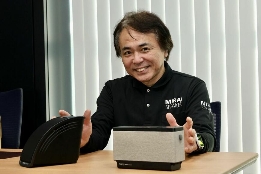 「ミライスピーカー・ミニ」と「キャリー・バイ・ミライスピーカー」について説明するミライスピーカー社広報の波多江良徳さん（写真：筆者撮影）