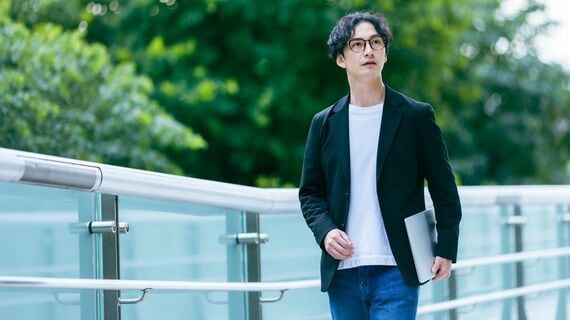 PCを片手に歩く男性