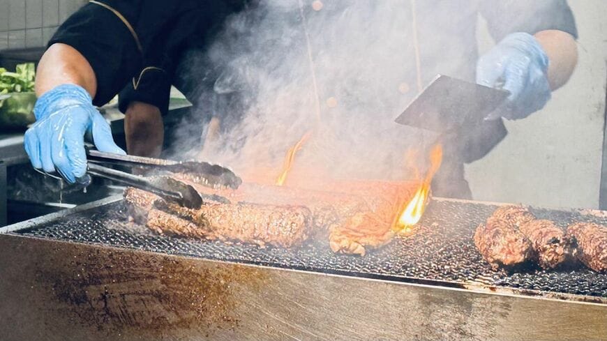 オープンキッチンの炭火グリル。入店直後から炎と煙が視界に飛び込んでくる（写真：筆者撮影）