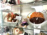 ​​これらのサンプルの巨大さは決して誇張ではないのがおぐら流。本当にこの通りの大きさのメニューが出てくる。サンプルの合間に置かれたぬいぐるみに心が和む（撮影：横田ちえ）​ 