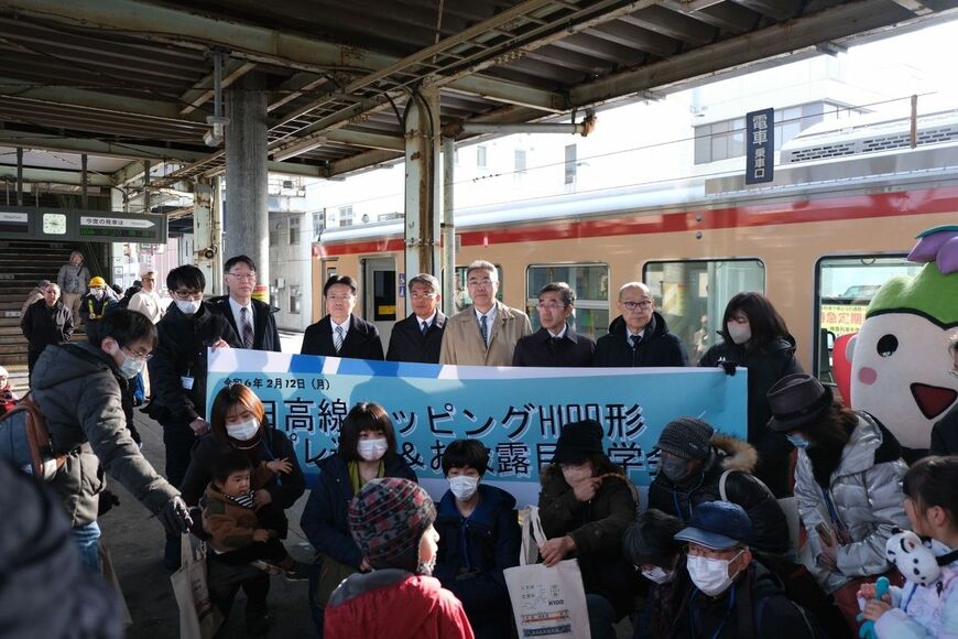 苫小牧市などの沿線市町の首長やキャラクターと記念撮影するプレ運行の乗客たち（筆者撮影）