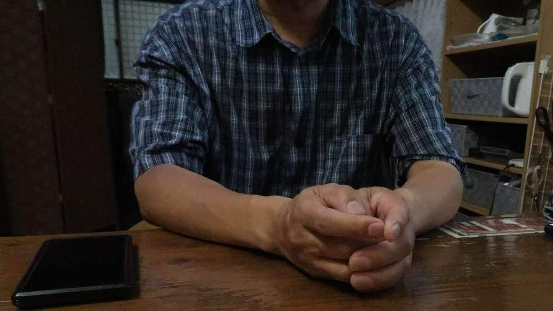 今回紹介するのは、57歳の男性ナオキさん(仮名)。非正規雇用のダブルワークで毎月の手取り額は約15万円。バイク通勤の影響で腕が日焼けしている(写真:編集部撮影)