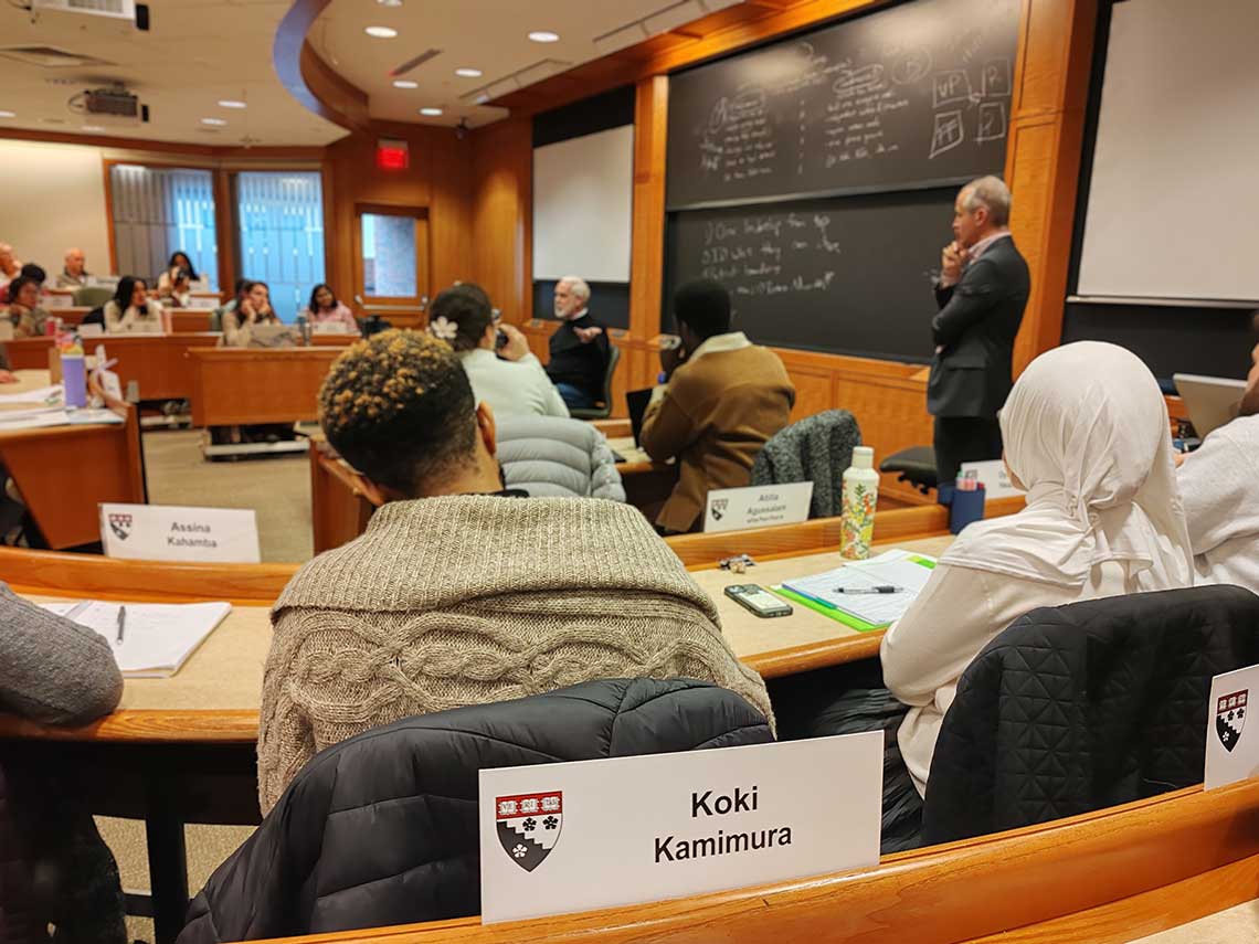 教室の風景。先生が黒板の前に立ち、世界各国から集まった学生が囲むように座っている