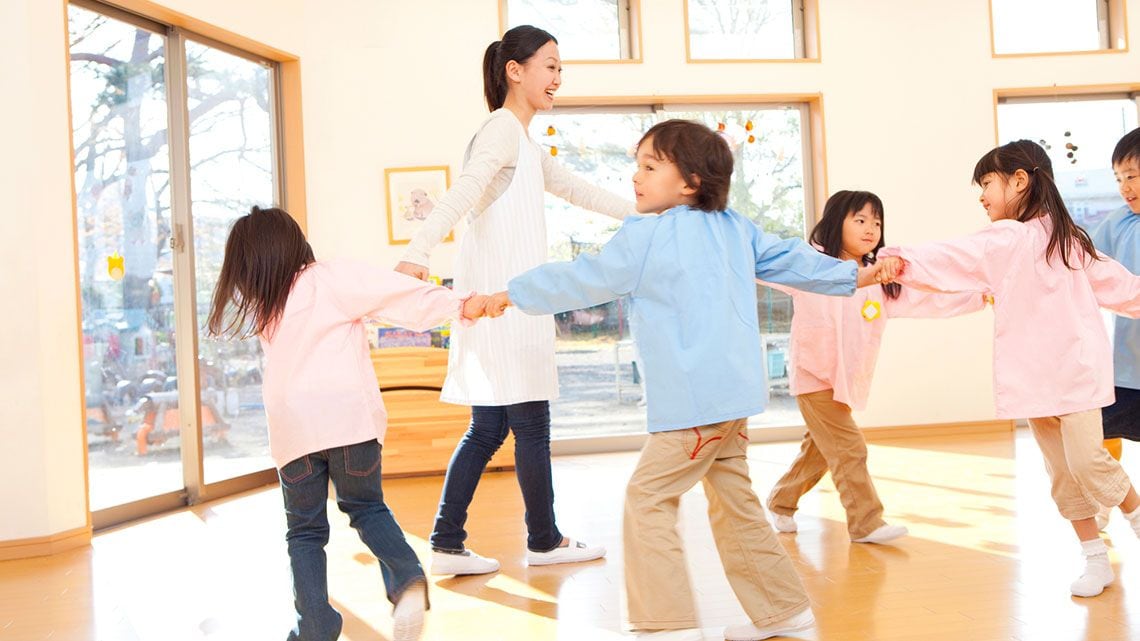 輪になって踊る幼稚園教諭と幼稚園児