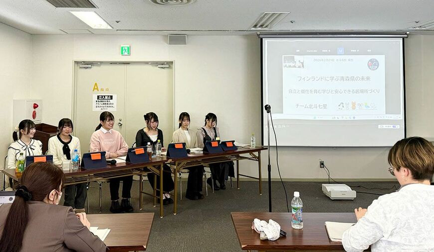 6人のチームメンバーが並んで発表をする様子