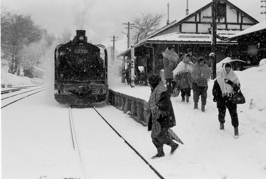 雪深い冬の会津線、湯野上駅（現・湯野上温泉駅）に着いたC11形の列車。すっぽりと防寒具に身を包んだ乗客たちは反対方向の気動車に乗り込む＝1972年（撮影：南正時）