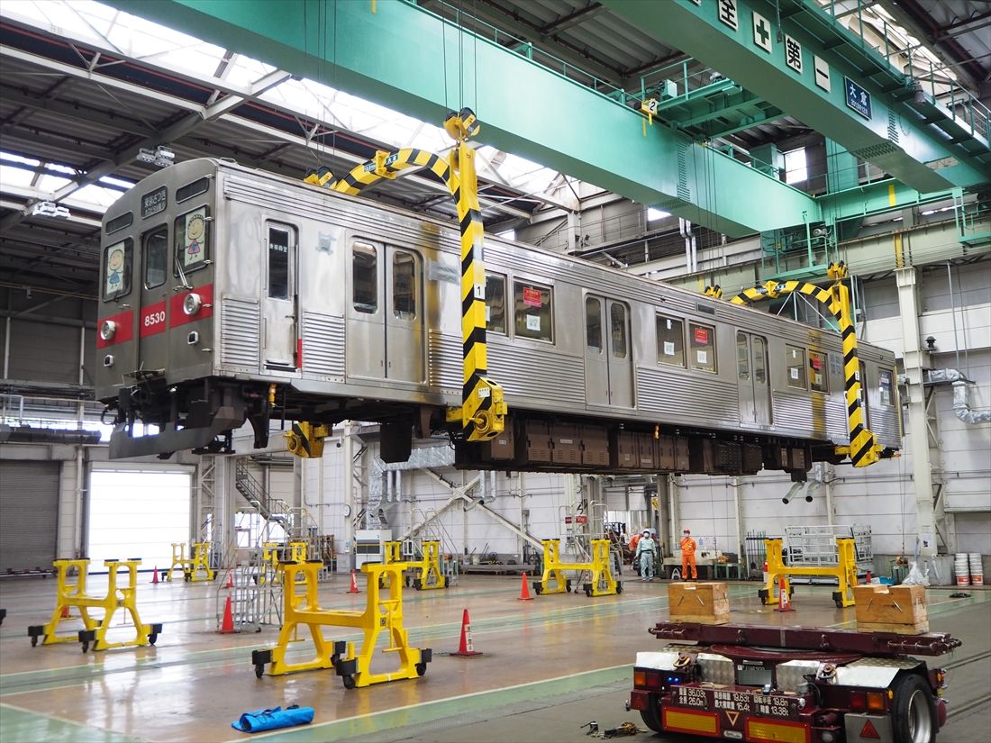 クレーンでゆっくりと吊り上げられる車体（記者撮影）