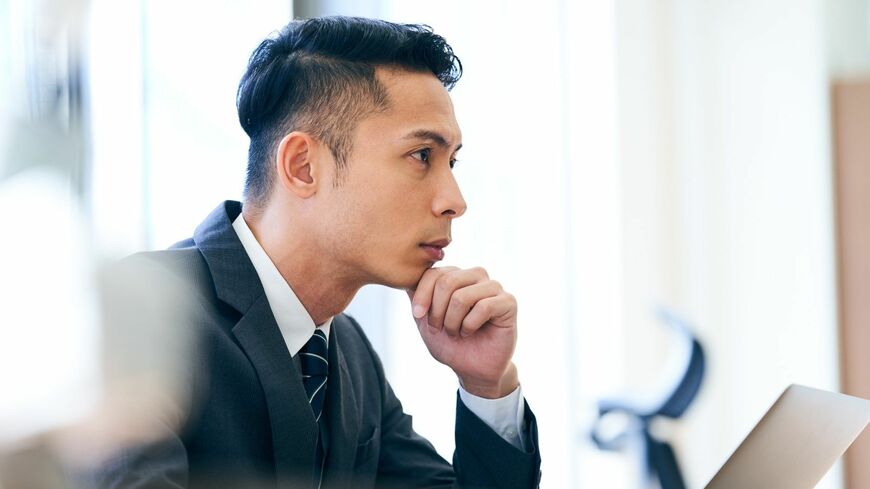 あごに手をつくスーツ姿の男性