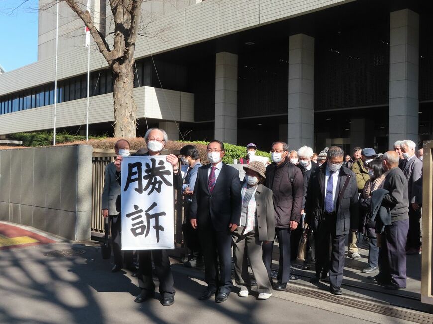 判決後、「勝訴」の旗を掲げる住民たちの表情は硬かった（撮影：河野博子）