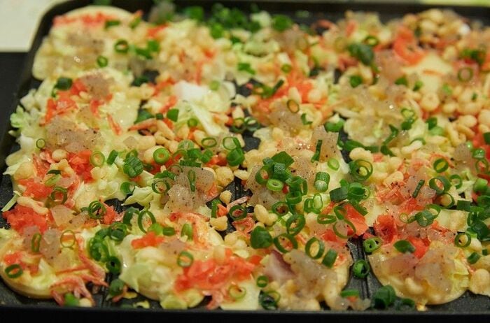 加熱しながら、たこ焼き器の丸い穴に生地を寄せていくと、