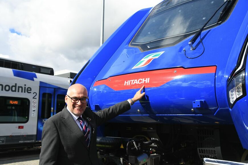 日立の新型車両「ブルース」と鉄道部門トップのバー氏（記者撮影）