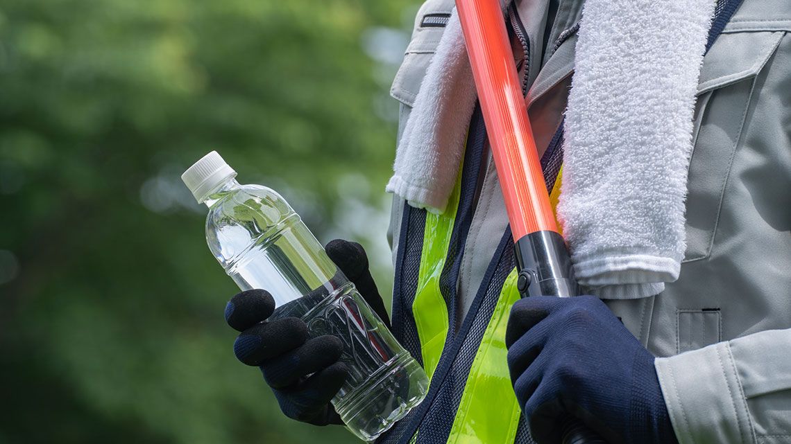 ペットボトルの水を持つ警備員の男性