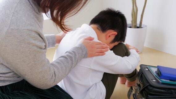 辛そうな小学生の男の子とその母親