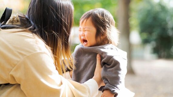 泣いている1歳の子どもをあやす母親
