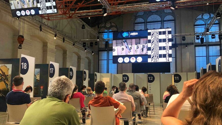 ワクチン接種会場、トリノの老舗コーヒー・メーカー「ラヴァッツァ」本社。巨大スクリーンにはラヴァッツァの宣伝がずっと流れていた（筆者撮影）