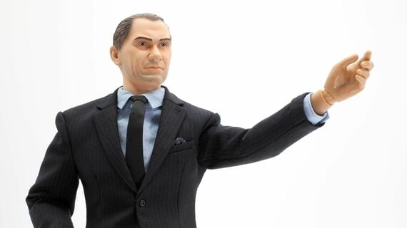 片手を挙げて演説するスーツを着た男性のフィギュア