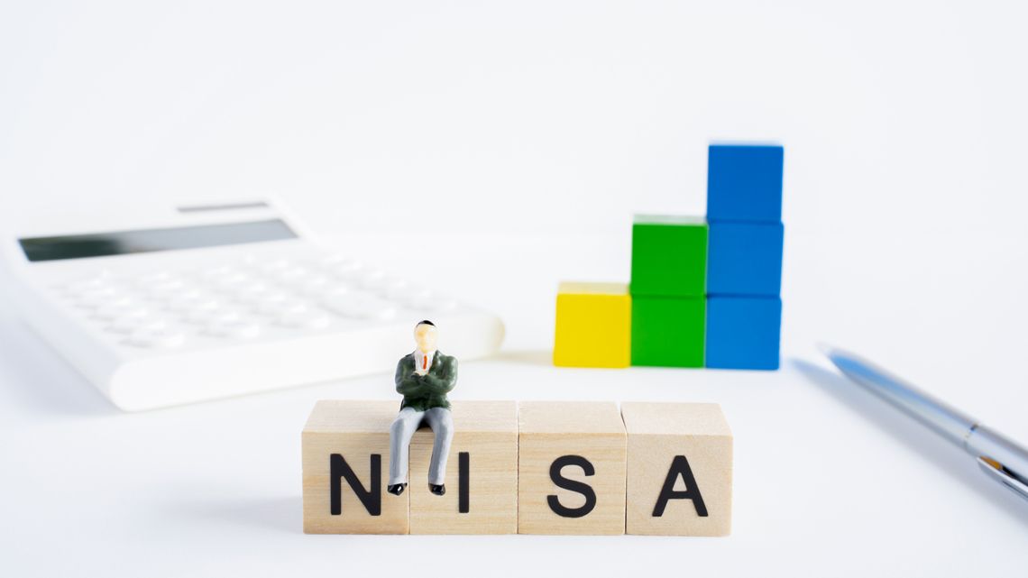 NISAと印字されたブロックに腰をかけるミニチュアの人形