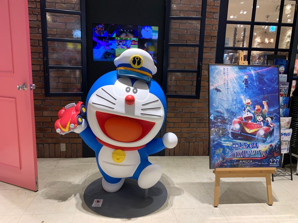未来デパートの入り口にいるカメレオン帽子を被ったドラえもん。手にはひみつ道具「海水バギー」を持っている（筆者撮影）