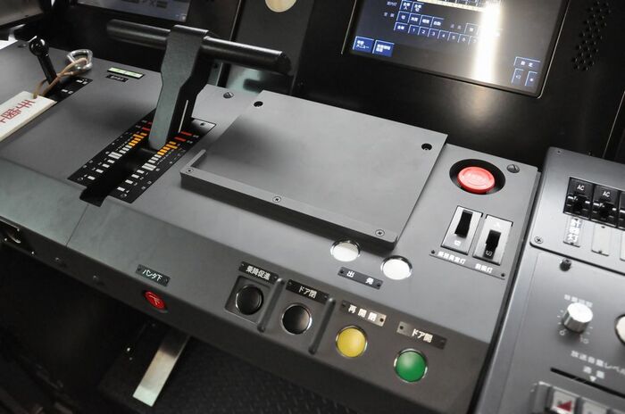 ドア開閉ボタン（右下）や赤い非常停止ボタンが並ぶ運転台