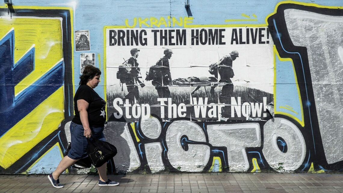 ウクライナのキエフで、独立記念日の前にフレシチャーティク通りにある反戦の壁画を通り過ぎる歩行者