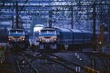 小雨の降る東京駅に到着したEF66形が牽引する「みずほ」。隣には「はやぶさ」のヘッドマークを付けたEF66形、そして後ろには0系新幹線が見える（撮影：橋爪智之）