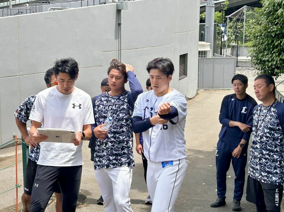iPadで録画し、選手に見せながら理想の走り方を教える秋本コーチ（左）