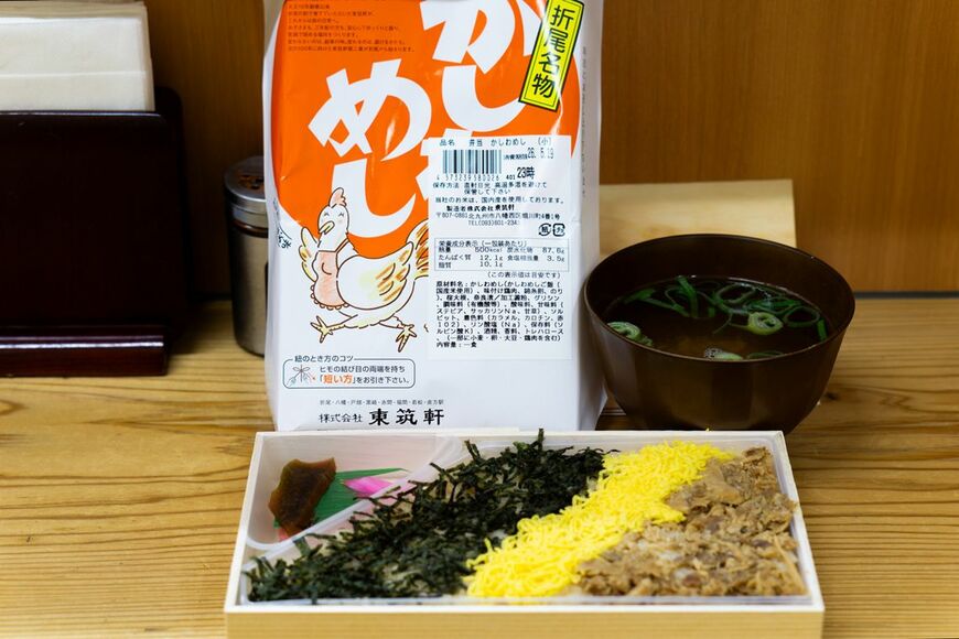 かしわめしの小（860円）とサービスのお吸い物。買った駅弁は「折尾駅うどん店」内で飲食可能で、お弁当購入者にはかしわ入りのお吸い物がつく。思いがけないもてなしだ。冷めているのにしっとりとほの甘いかしわめしに、錦糸卵がやさしく寄り添う。海苔はきりりと味を締める。なるほど、これが「冷めてもうまい」かしわめし（写真：筆者撮影）